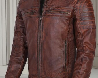May include: A brown leather jacket with a stand-up collar and a zip-up front. The jacket has multiple zippered pockets and quilted detailing on the shoulders and sleeves. The leather has a distressed appearance.