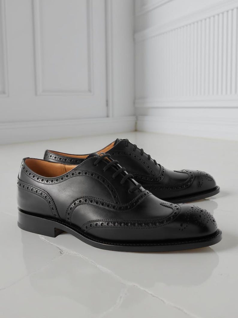 May include: A pair of black leather Oxford shoes with brogue detailing. The shoes feature a classic wingtip design with decorative perforations along the seams and toe cap. The shoes have black laces and a low heel.