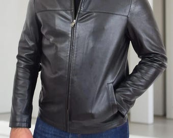 Può includere: Giacca in pelle nera con collo e chiusura a zip. La giacca ha due tasche anteriori e viene indossata con jeans blu. Uno stile classico.
