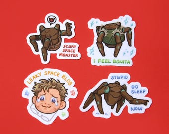 May include: Four stickers on a red background. The stickers feature cartoon illustrations of space-themed creatures and a crying person. Text on the stickers includes "SCARY SPACE MONSTER", "I FEEL BONITA", "LEAKY SPACE BLOB", "STUPID GO SLEEP NOW".