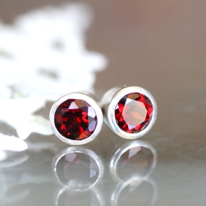 May include: A pair of silver stud earrings with round red gemstones.