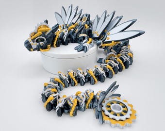 May include: A 3D printed steampunk dragon figurine with a silver and gold finish. The dragon has wings, a long tail, and a detailed head with gears and other mechanical elements.