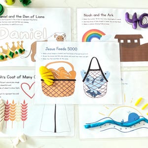 Puede incluir: Hojas de actividades educativas con elementos de plastilina de colores. Las hojas representan historias bíblicas como Daniel y el foso de los leones, Noé y el arca, la túnica de José y Jesús alimenta a 5000. Incluye una corona, un león, un arcoíris, un arca, espigas de trigo, pan, peces y una ballena.