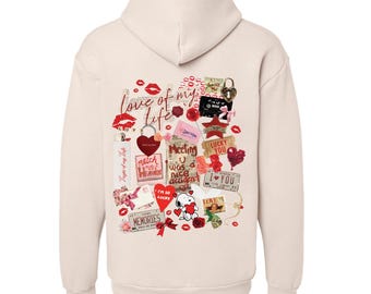 May include: A cream-colored hoodie with a collage of red and pink hearts, lips, and other Valentine's Day themed imagery. The text "love of my life" is featured on the back of the hoodie.