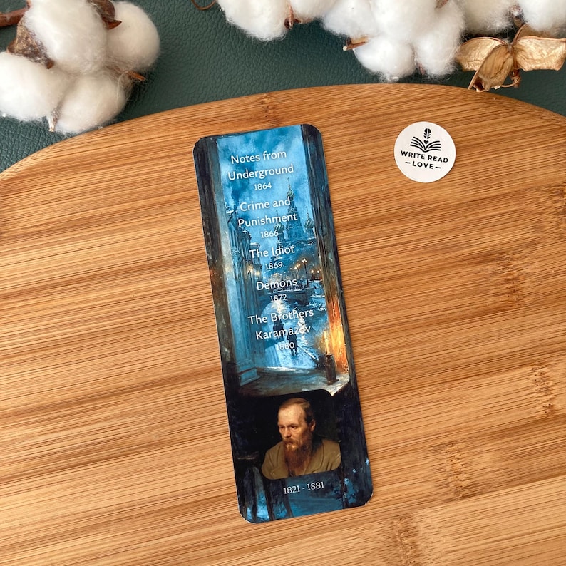 May include: A rectangular bookmark featuring a portrait of a man and a list of book titles. The titles include "Notes from Underground," "Crime and Punishment," and "The Brothers Karamazov." The bookmark has a blue and brown color scheme.