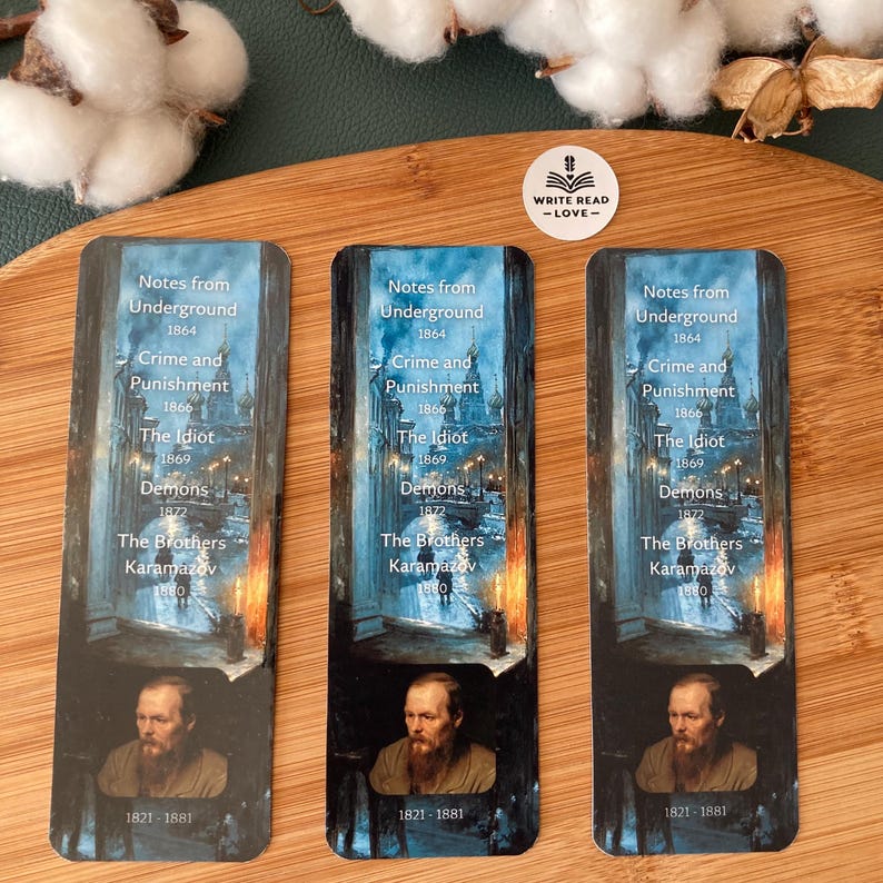 May include: Three rectangular bookmarks featuring a portrait of a man and titles of literary works. The titles include "Notes from Underground," "Crime and Punishment," and "The Brothers Karamazov." The bookmarks have a dark, artistic design.