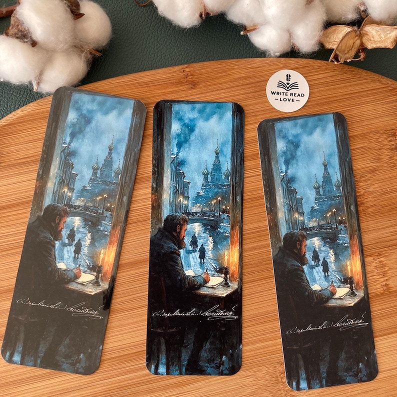 May include: Three rectangular bookmarks featuring a detailed illustration of a man writing at a desk, with a cityscape visible through a window. The scene is rendered in cool tones, with a church in the background. The text "WRITE READ -LOVE-" is on one bookmark.