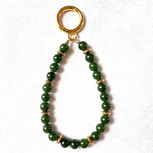 May include: A green jade beaded keychain with gold accents and a gold metal clasp.