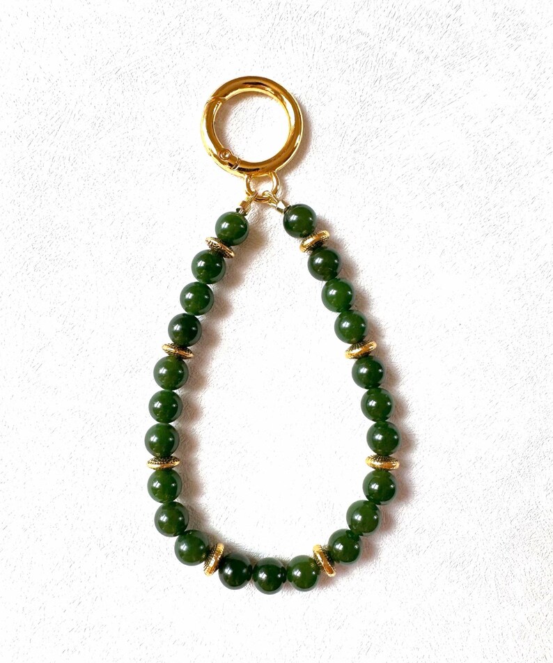 May include: A green jade beaded keychain with gold accents and a gold metal clasp.