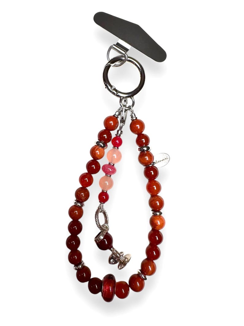 May include: A red, orange and pink beaded keyring with a silver charm of a wine glass. The keyring is attached to a silver ring.