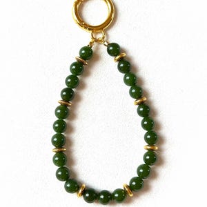 May include: A green jade beaded keychain with gold accents and a gold metal clasp.
