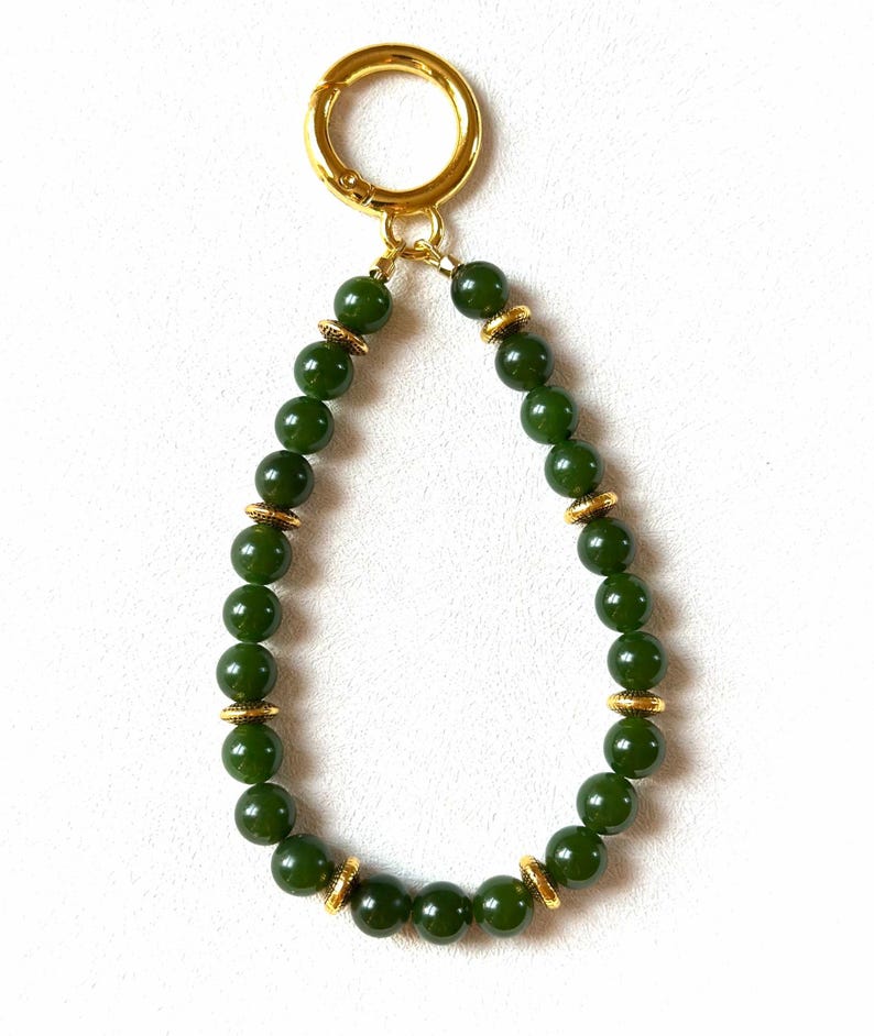 May include: A green jade beaded keychain with gold accents and a gold metal clasp.