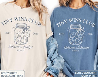 May include: Two crewneck t-shirts, one ivory with blue ink and one blue with ivory ink. Both feature a graphic of a mason jar filled with stars, the text "TINY WINS CLUB", "EST. 2026", and "Behavior Analyst" or "Behavior Technician" with names.