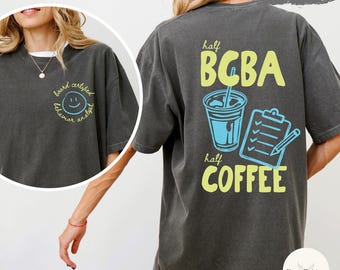 May include: Pepper-colored t-shirt with a graphic on the back that says "half BCBA half COFFEE" with a coffee cup and clipboard illustration. The front has a smiley face and the words "board certified behavior analyst".