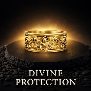 Puede incluir: Un anillo dorado con un dise&ntilde;o grabado que presenta una figura de &aacute;ngel y motivos florales. El anillo se exhibe sobre una superficie oscura y texturizada con las palabras "DIVINE PROTECTION" debajo. El anillo est&aacute; iluminado con una luz c&aacute;lida.