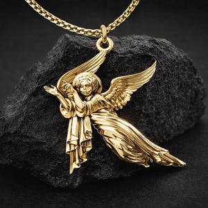 Puede incluir: Un collar con colgante dorado con un dije en forma de &aacute;ngel. El &aacute;ngel tiene alas extendidas y est&aacute; suspendido de una delicada cadena. El colgante se muestra sobre una roca oscura y texturizada sobre un fondo negro.
