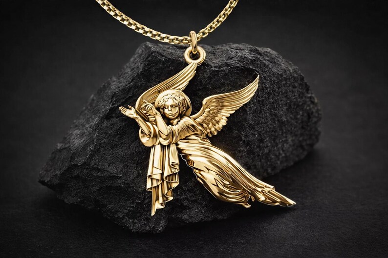 Puede incluir: Un collar con colgante dorado con un dije en forma de &aacute;ngel. El &aacute;ngel tiene alas extendidas y est&aacute; suspendido de una delicada cadena. El colgante se muestra sobre una roca oscura y texturizada sobre un fondo negro.