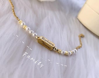 May include: A gold chain bracelet with white pearls and a gold bar charm engraved with the names "Barbara Thomas" and the word "Family".