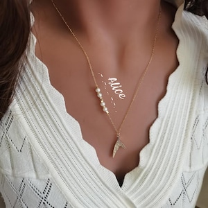 Pode incluir: Um colar de corrente dourada com um pequeno charme de cauda de sereia brilhante e uma fileira de pérolas brancas. O colar tem o nome "Alice" escrito nele.