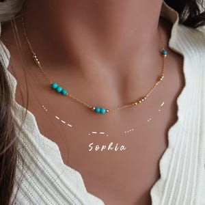 May include: A gold chain necklace with turquoise beads. The necklace has the name "Sophia" written below it.