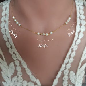 Könnte beinhalten: Eine goldene Kettenkette mit kleinen weißen Perlen. Die Kette trägt drei Namen: David, Linda und Rose.