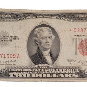 May include: A vintage two dollar bill with a portrait of Thomas Jefferson. The bill is in good condition and has a serial number of 03371509 A. The text "UNITED STATES OF AMERICA WILL PAY TO THE BEARER ON DEMAND TWO DOLLARS" is printed on the bill.