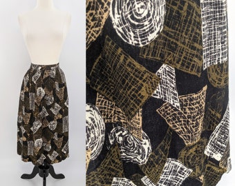 Op de afbeelding: Een vintage midi-rok met een zwarte achtergrond en een herhalend patroon van geometrische vormen in wit, bruin en beige. De rok wordt gepresenteerd op een mannequin tegen een witte achtergrond. De rok heeft een hoge taille en een lichte A-lijn vorm.