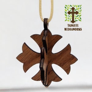 May include: A wooden pendant in the shape of a cross with a decorative design. The pendant is brown and has a cord attached to it.