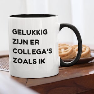 Könnte beinhalten: Weißer Keramikbecher mit schwarzem Innenraum und Henkel. Der Becher trägt den schwarzen Text "GELUKKIG ZIJN ER COLLEGA'S ZOALS IK". Im Hintergrund sind zwei Gebäckstücke auf einem Teller zu sehen.