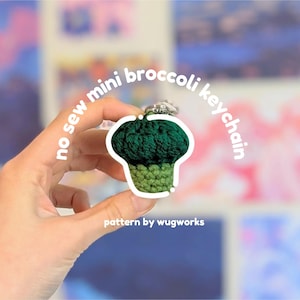 May include: A handmade, no-sew mini broccoli keychain. The keychain is green and light green, with a white outline. The text "no sew mini broccoli keychain" and "pattern by wugworks" are also visible.