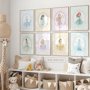 May include: Eight framed princess art prints in pastel colors, each featuring a different princess in an oval frame. The prints are displayed on a white wall above a white shelf with decorative items and baskets. The text "MORE PRINCESSES" is visible.