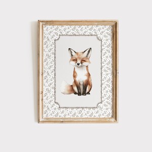 May include: A framed watercolor print of a fox. The fox is depicted with closed eyes and a gentle smile, with a fluffy tail. The frame is a light wood color, and the print has a decorative border with a leaf pattern.