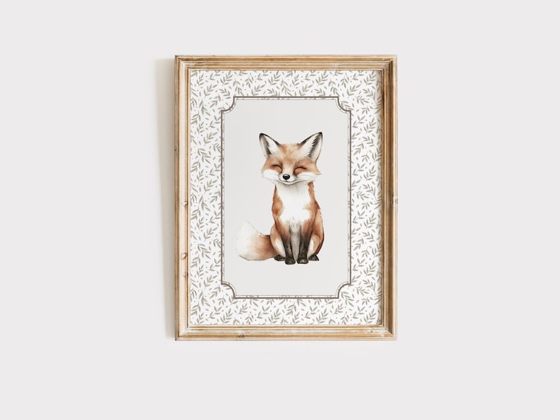 May include: A framed watercolor print of a fox. The fox is depicted with closed eyes and a gentle smile, with a fluffy tail. The frame is a light wood color, and the print has a decorative border with a leaf pattern.