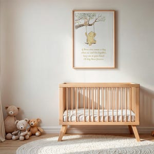 May include: A nursery scene featuring a light wood crib with a mattress, a framed Winnie the Pooh print, and several teddy bears. The print shows Pooh on a swing. A white rug and a woven basket complete the cozy, neutral-toned decor.