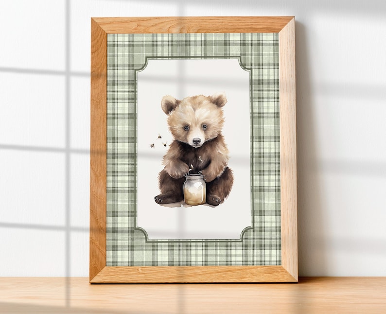May include: A framed watercolor print featuring a brown bear cub holding a jar of honey. The artwork is set against a white background with a green plaid border and a natural wood frame. The image has a whimsical, childlike quality.