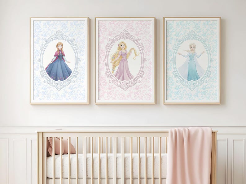 May include: Three framed art prints featuring illustrations of princesses. Each print has a different princess in an oval frame, set against a patterned background. The frames are gold-colored, and the prints are displayed above a crib.