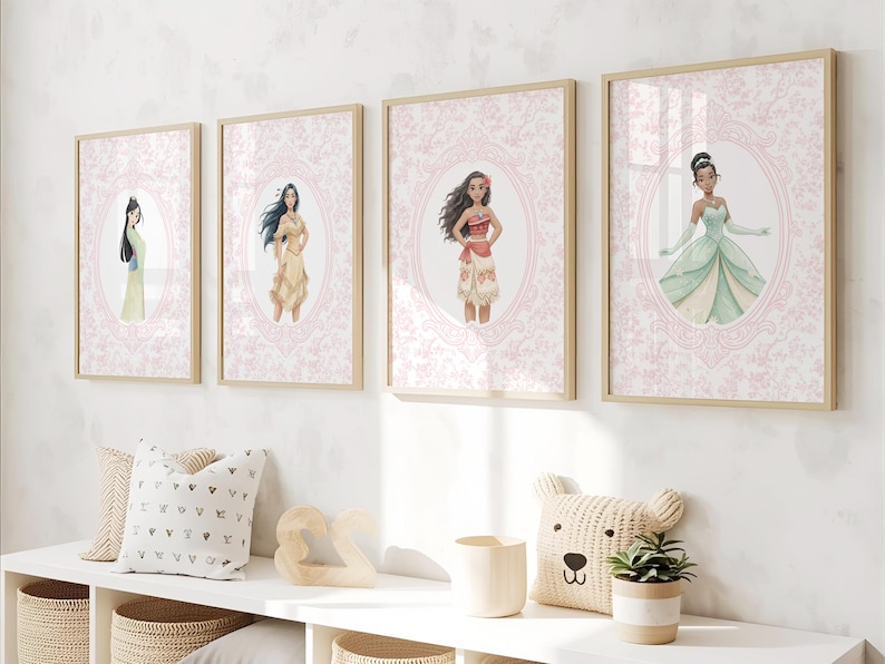May include: Four framed art prints featuring watercolor illustrations of animated characters. Each print has a light wood frame and a pink floral background. The characters are in oval frames. Decorative pillows and a bear-shaped pillow are on a white shelf.