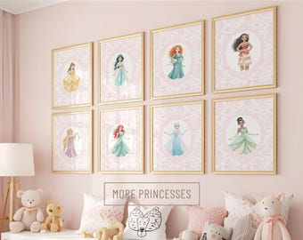 May include: A set of eight framed wall art prints featuring illustrations of various princesses in oval frames with a pink damask background. Each print is encased in a thin gold frame. The text MORE PRINCESSES is centered below the prints.