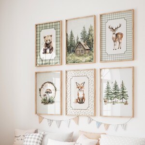 May include: Six framed art prints with woodland animal and forest scenes. The prints feature a bear, a cabin, a deer, a fox, a mushroom, and trees. The frames are light brown, and the artwork has a watercolor style with green and brown tones.