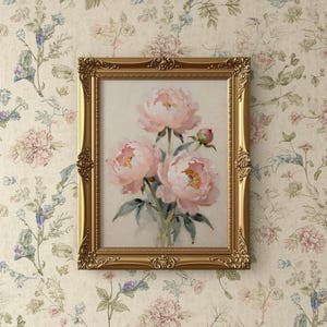 Peut inclure: Une impression florale encadr&eacute;e repr&eacute;sentant trois pivoines roses avec des feuilles vertes. L'&oelig;uvre est encadr&eacute;e dans un cadre dor&eacute; orn&eacute; et est accroch&eacute;e sur un fond de papier peint floral.