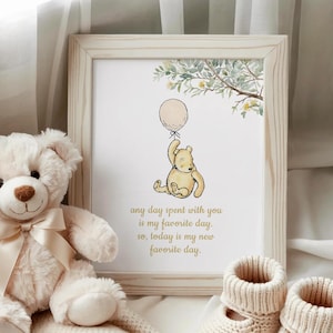 May include: A framed print featuring Winnie the Pooh holding a balloon, with the text "any day spent with you is my favorite day. So, today is my new favorite day." A plush teddy bear and baby booties are also in the image.