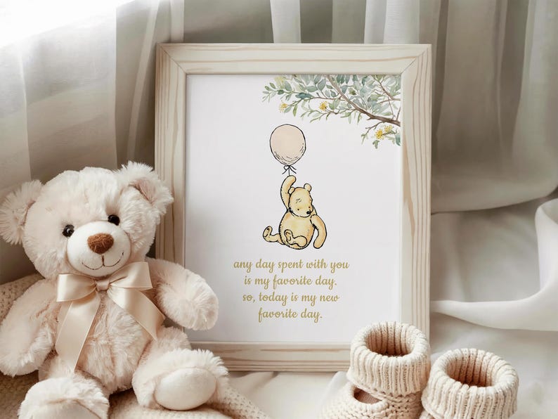 May include: A framed print featuring Winnie the Pooh holding a balloon, with the text "any day spent with you is my favorite day. So, today is my new favorite day." A plush teddy bear and baby booties are also in the image.