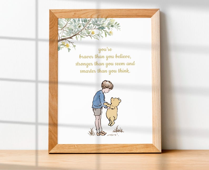 May include: A framed print featuring a watercolor illustration of a boy and a bear. The boy, in a blue shirt and shorts, holds the bear. The print includes the text: "You're braver than you believe, stronger than you seem and smarter than you think."