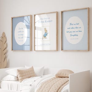 Puede incluir: Tres impresiones enmarcadas con marcos de madera clara cuelgan sobre una cama blanca. Las impresiones presentan patrones y citas en azul y blanco. La impresi&oacute;n central es una portada del libro "The Tale of Peter Rabbit".