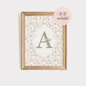 Peut inclure: Impression florale encadr&eacute;e avec la lettre "A" en vert sauge, orn&eacute;e d'un n&oelig;ud rose. La lettre est entour&eacute;e d'une couronne de roses roses et de feuilles vertes. L'impression est dans un cadre en bois, avec le texte "A-Z included" dans un cercle rose.
