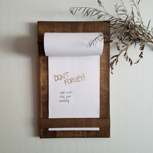 May include: A wooden memo board with a roll of paper attached. The paper has a handwritten to-do list that says "DON'T FORGET!" and includes items like "call mom", "dog food", and "laundry".