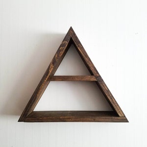 May include: A triangular wooden shelf with two shelves. The shelf is stained a dark brown color and has a rustic look.