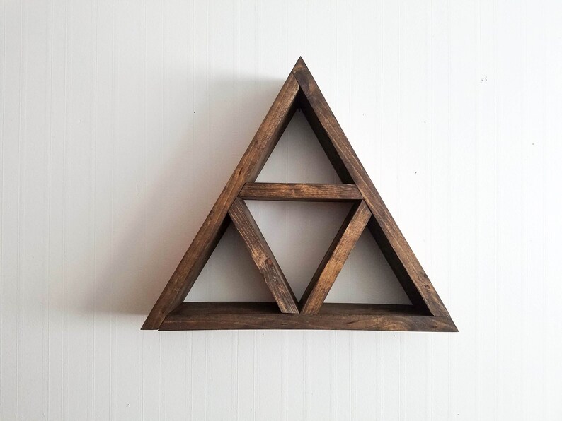 May include: A dark brown wooden triangle shelf with three shelves. The shelf is mounted on a white wall.