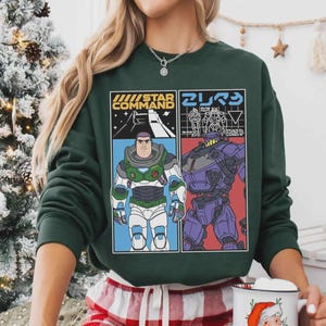 May include: Dark green sweatshirt with a graphic design. The left panel says "STAR COMMAND" and features a cartoon character in a space suit. The right panel has Japanese text and a purple robot.