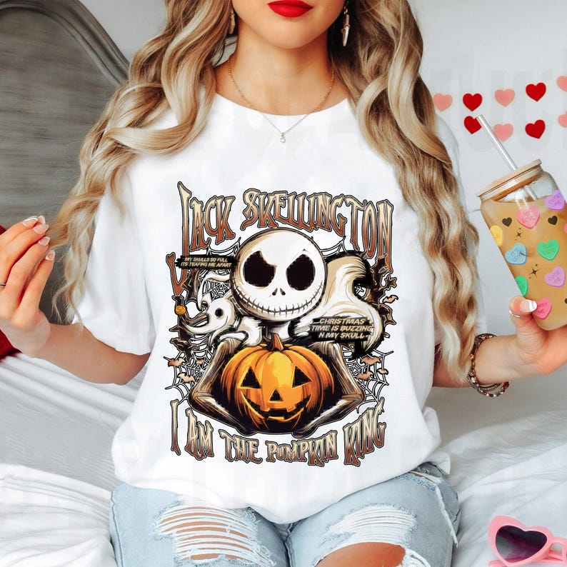 Puede incluir: Camiseta blanca con un dise&ntilde;o de Jack Skellington de The Nightmare Before Christmas. El dise&ntilde;o incluye la cara de Jack, una calabaza y el texto "I AM THE PUMPKIN KING". El dise&ntilde;o es en negro, naranja y marr&oacute;n.